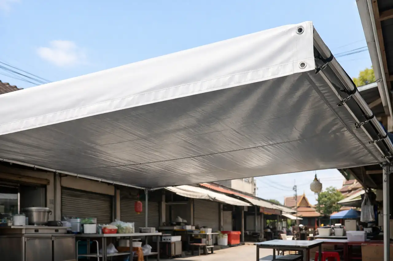 ผ้าใบ PVC สีขาวขึงเป็นร่มเงาในตลาด เห็นด้านล่างสีเงิน